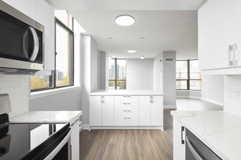 an empty kitchen with white cabinets and a window